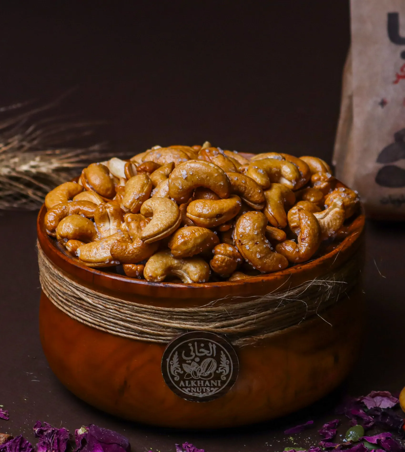 كاجو مغلّف بطبقة دهبية لمّاعة عليها حبيبات بيضا بزبدية خشب ملفوفة بخيط خيش وعليها ختم الخاني