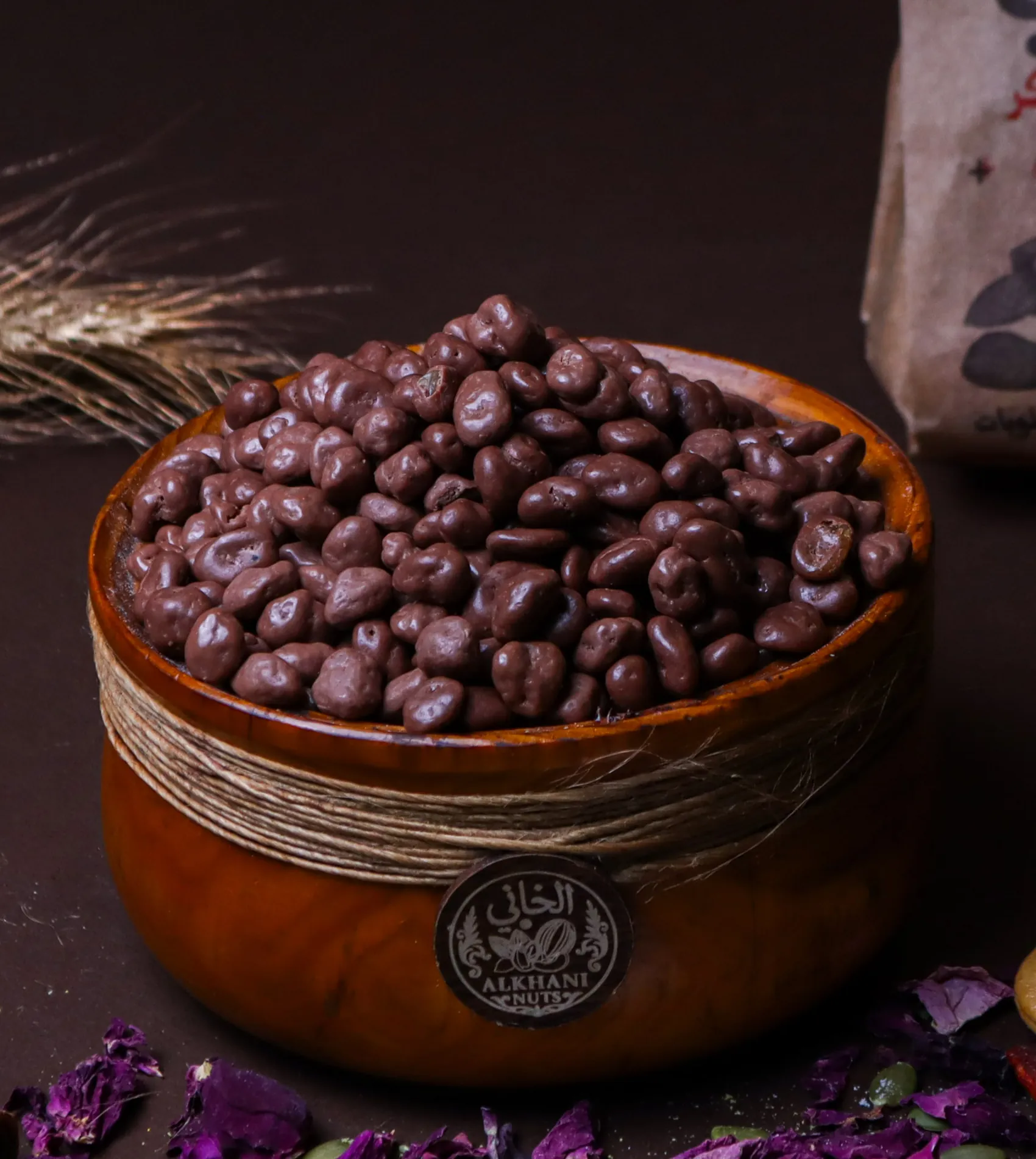 ملبّس شوكولا، حبات بنية مغطّاية شوكولا بأشكال مختلفة، بزبدية خشب ملفوفة بخيط خيش وعليها ختم الخاني